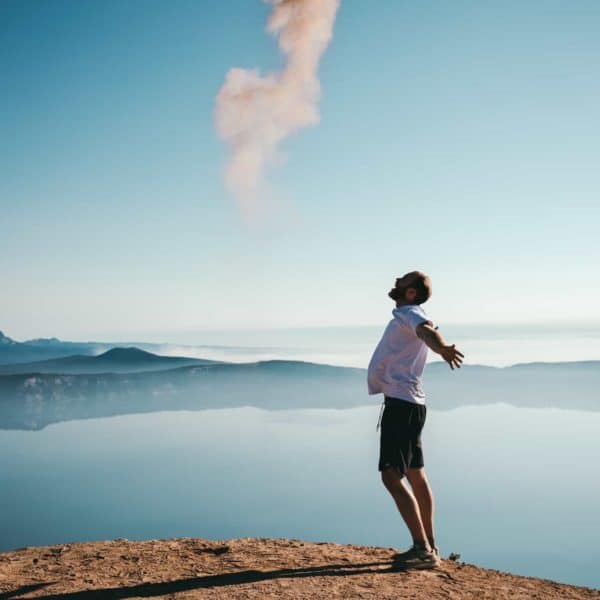 A man standing on a cliff edge looking happy