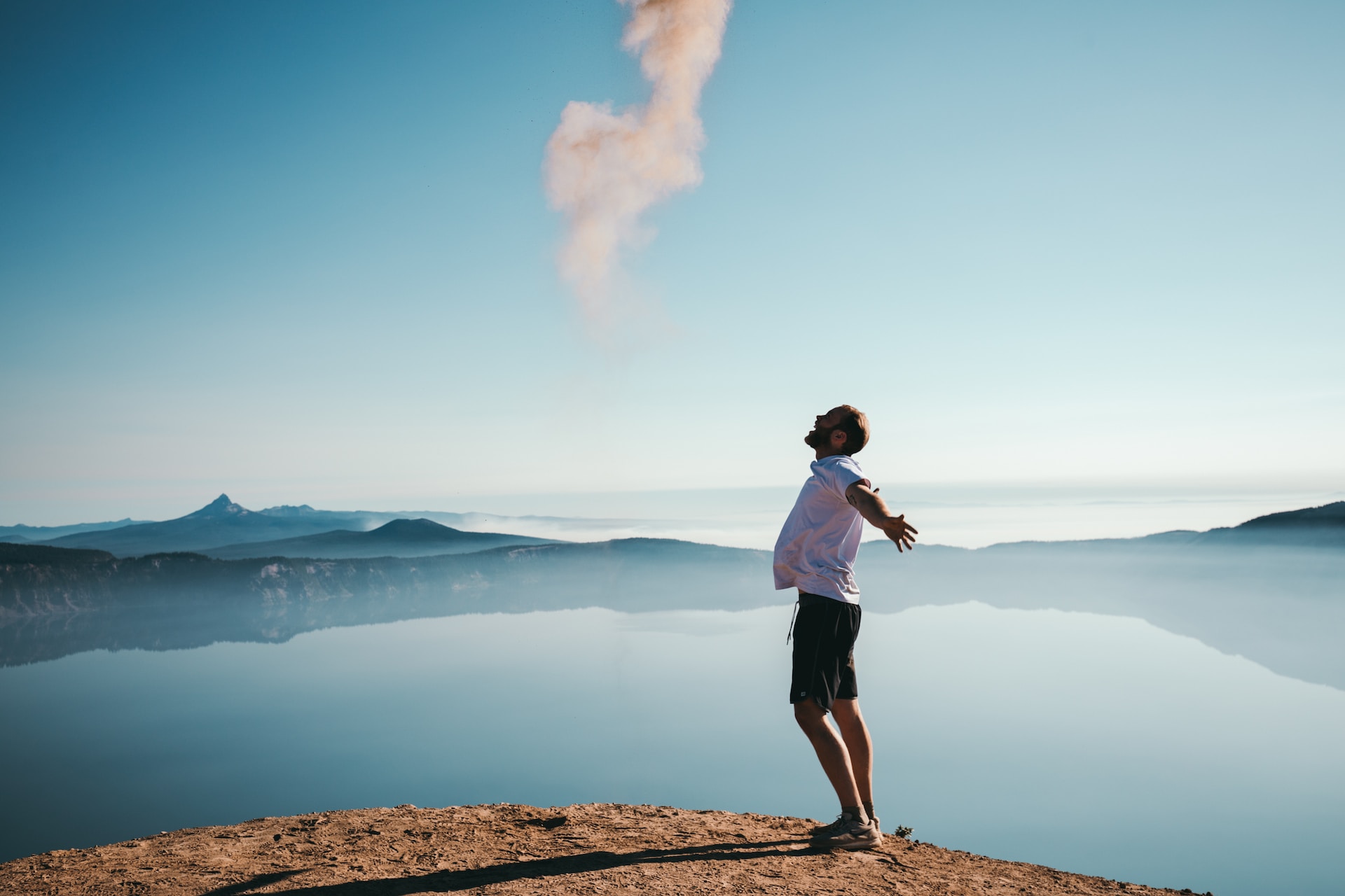 A man standing on a cliff edge looking happy