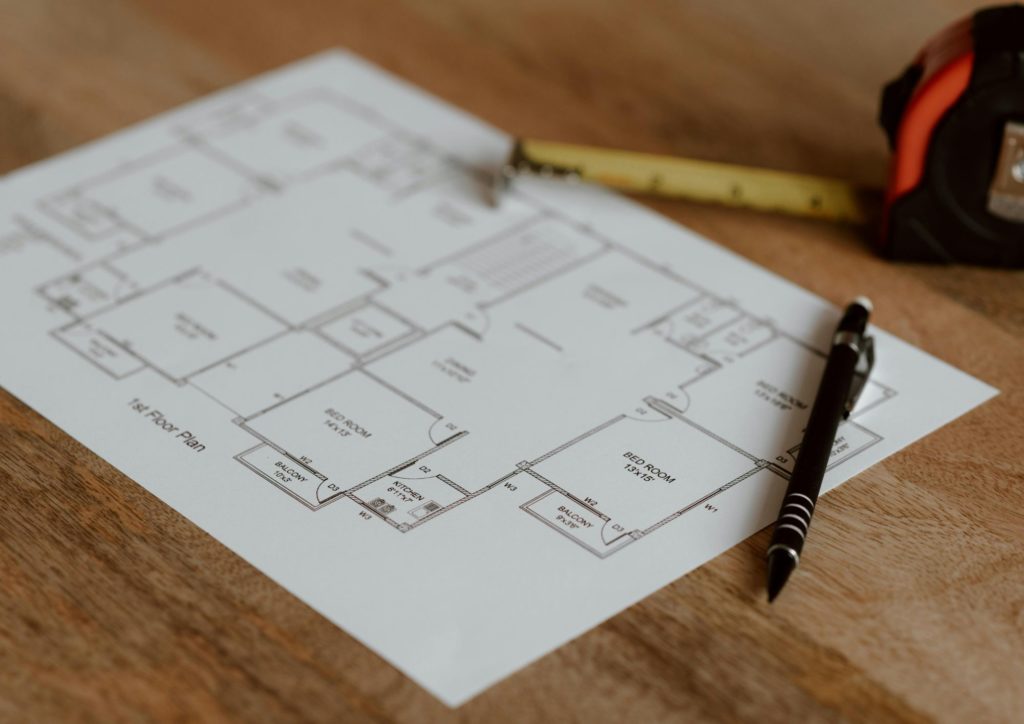 A floorplan laying on a table, with a measuring tape and pen laid over the top.